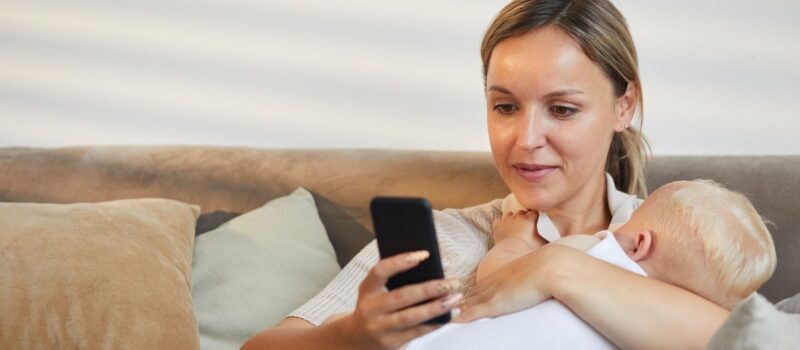 Moeder met baby en smartphone. Bron: Canva