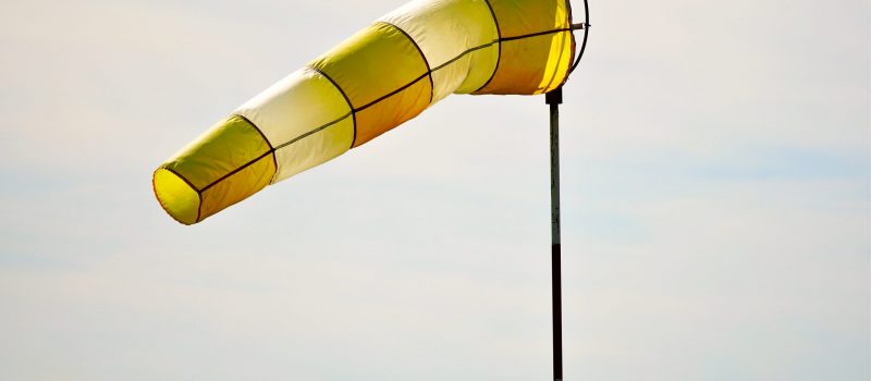 A closeup of a yellow and white windsock floating in the air during daylight