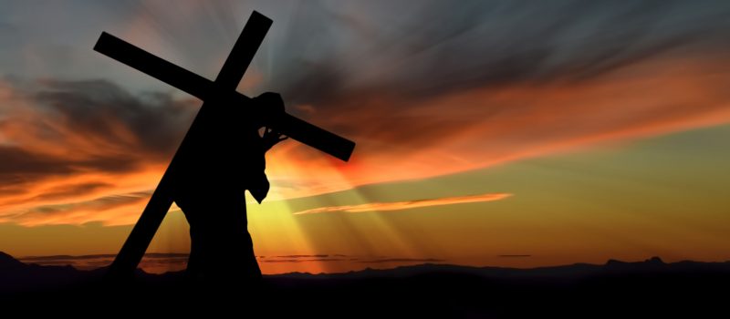 Christ carrying cross up Calvary on Good Friday over dark and stormy sky