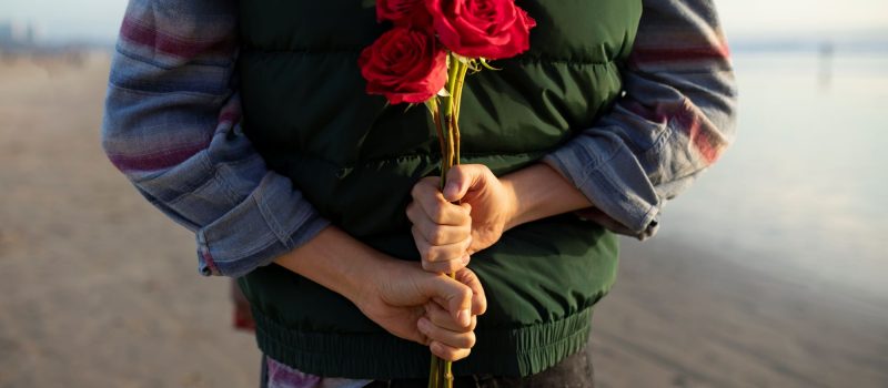 man houdt rozen op zijn rug voor date_Bron-Freepik