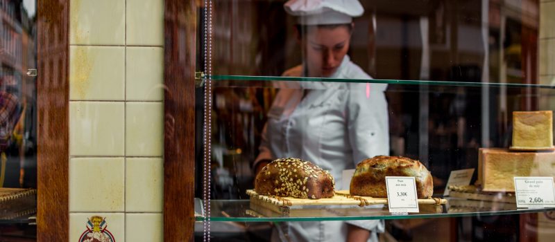 Bakker in winkel achter etalage met brood