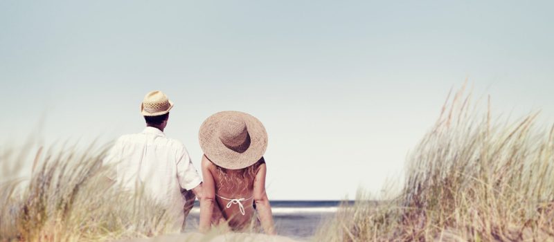 rear-view-couple-sitting-together-beach